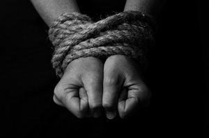 Conceptual monochrome image of woman hands tied 